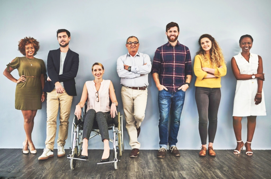Un grupo de personas posa de pie para la foto, una mujer en silla de ruedas.